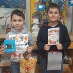 Dwaj chłopcy trzymający dyplomy i torby z prezentami